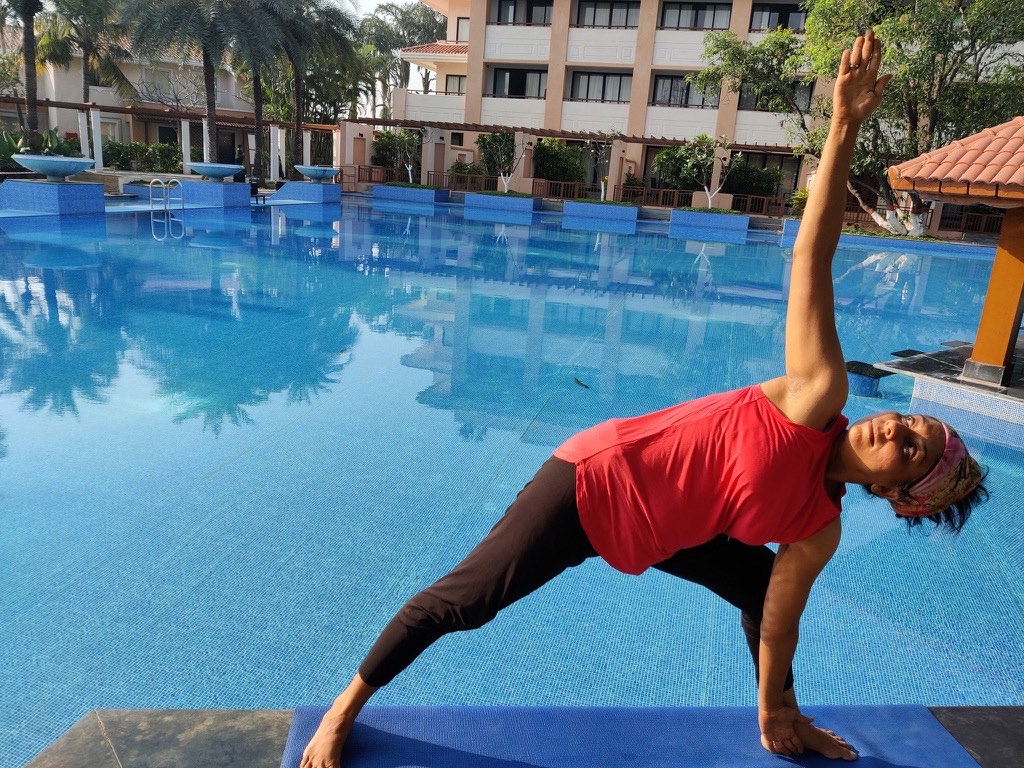Sheetal Mody in extended side angle pose beside a pool